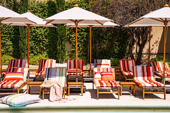 Outdoor seating area with Les Toiles du Soleil striped chairs and umbrellas by a pool