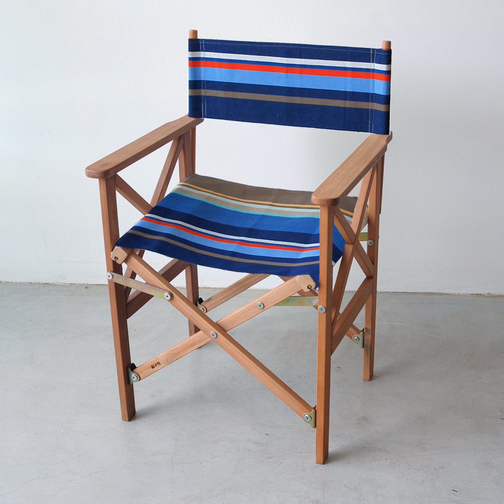 Ici et la teak director's chair made from Collioure Roy - a fabric featuring a striped pattern with various bands in different shades of blue, beige, brown and red. A detailed 100% cotton weave by By Les Toiles du Soleil 