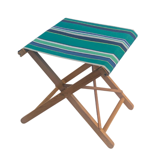 A folding teak wooden stool with a striped cotton Les Toiles du Soleil fabric seat cushion in shades of teal, green, blue, and white, shown on a plain white background.