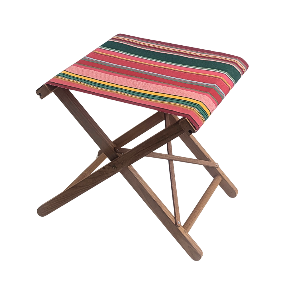 A teak folding stool  with Les Toiles du Soleil cotton fabric featuring stripes of red, crimson, candy pink, green, blue and golden yellow, inspired by the colours of the Catalan town of Toulouges and its famous onion.