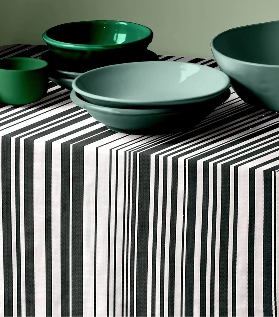 Tom Black multi striped black and white tablecloth by Les Toiles du Soleil. The setting has green ceramic bowls on top