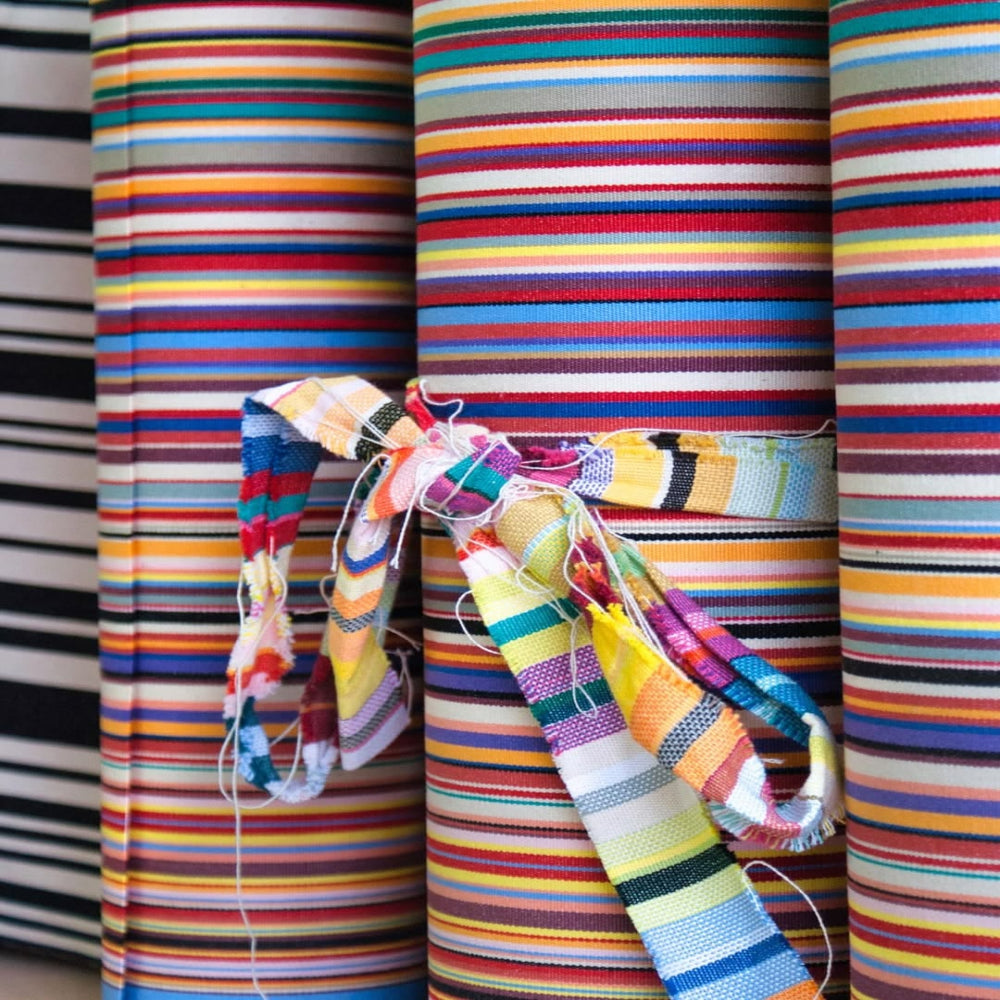 Close up of Tom Multi fabric featuring a multicolored striped pattern with various bands in different colors, indicating a vibrant and lively design. By Les Toiles du Soleil