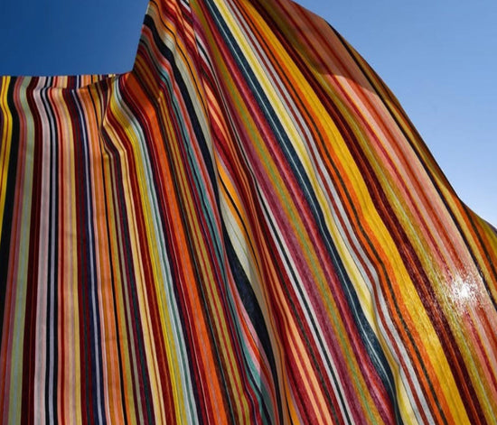 Tom-multi multicoloured striped Les Toiles du Soleil fabric against a clear blue sky