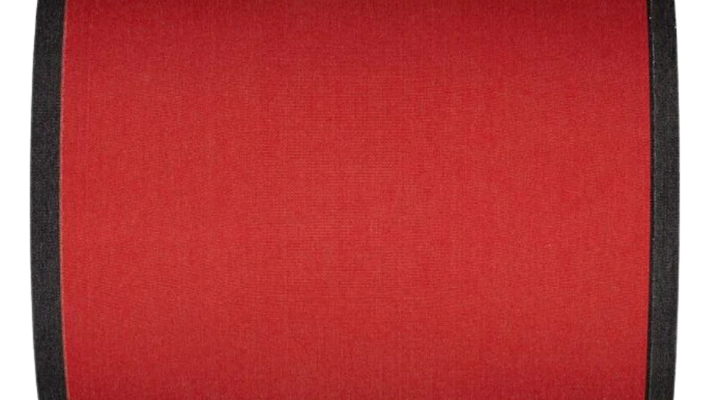 
Cotton fabric roll in a plain warm terracotta red with bold black selvedge edges.