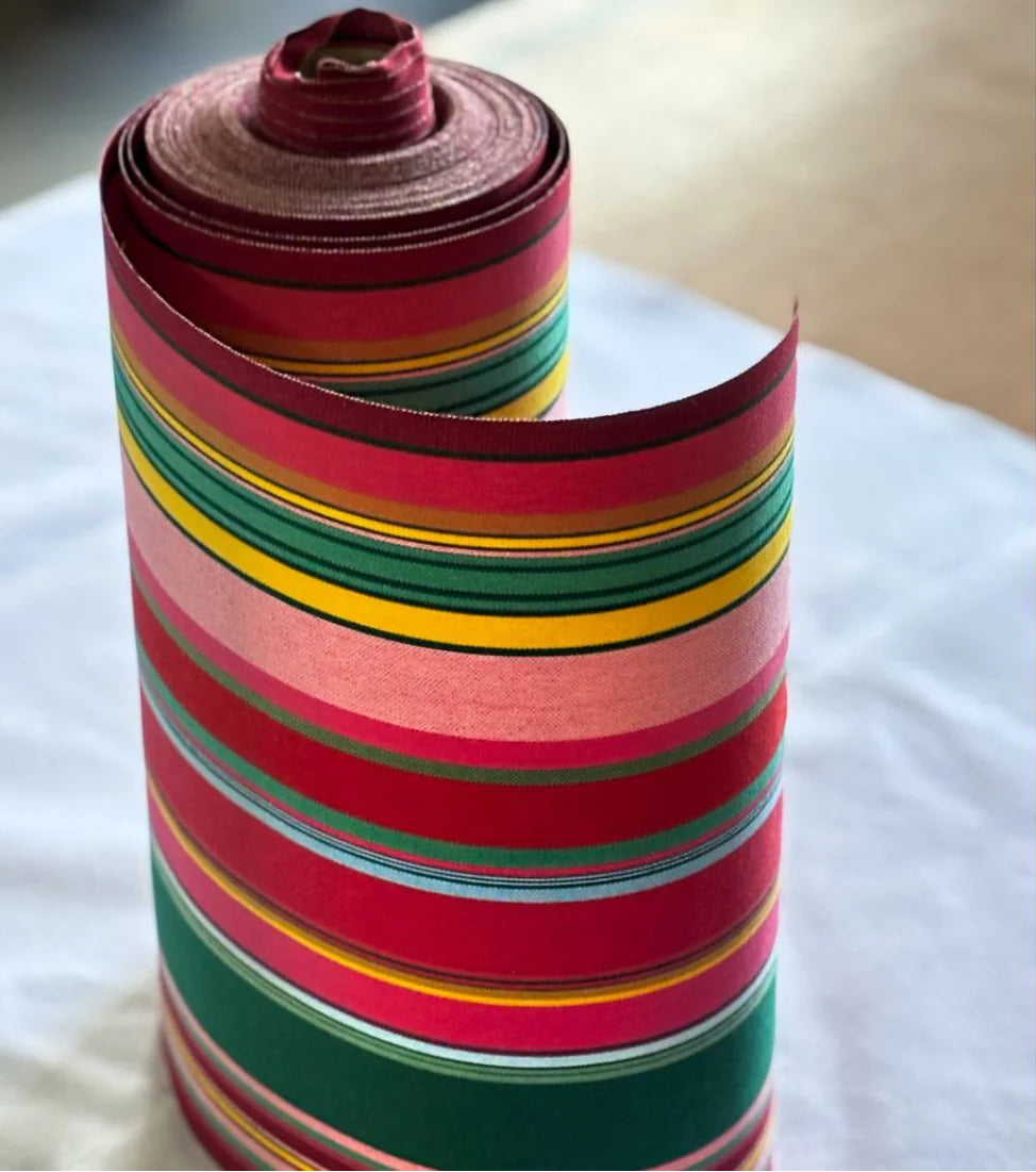 Cotton fabric roll featuring stripes of red, purplish crimson, candy pink, green, blue and golden yellow, inspired by the colours of the Catalan town of Toulouges and its famous onion.