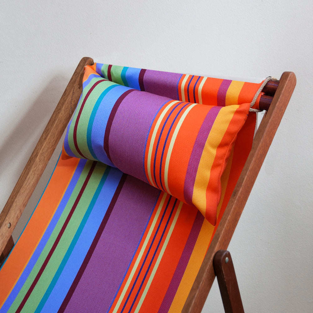 Bonbon Plume Sunbrella fabric of multiple colours such purple, orange, and blue, made into am ici et la head pillow and deckchair sling